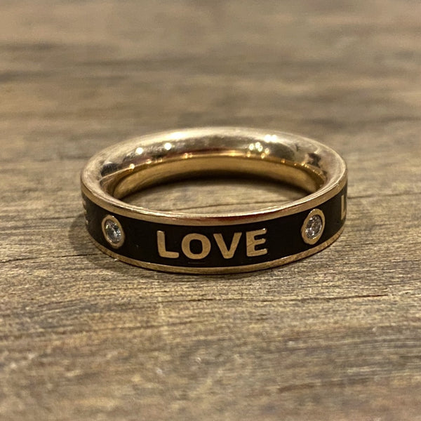 A rose gold ring with black enamel and the word 'LOVE' inscribed on it, featuring small diamonds on either side.